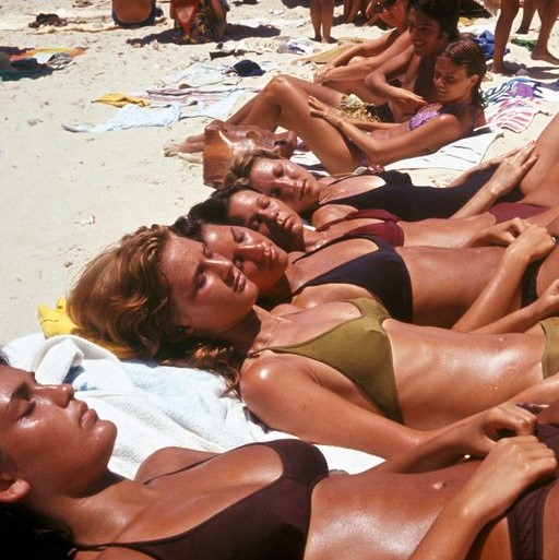 young women getting tan on beach.  Are they using sunscreen?