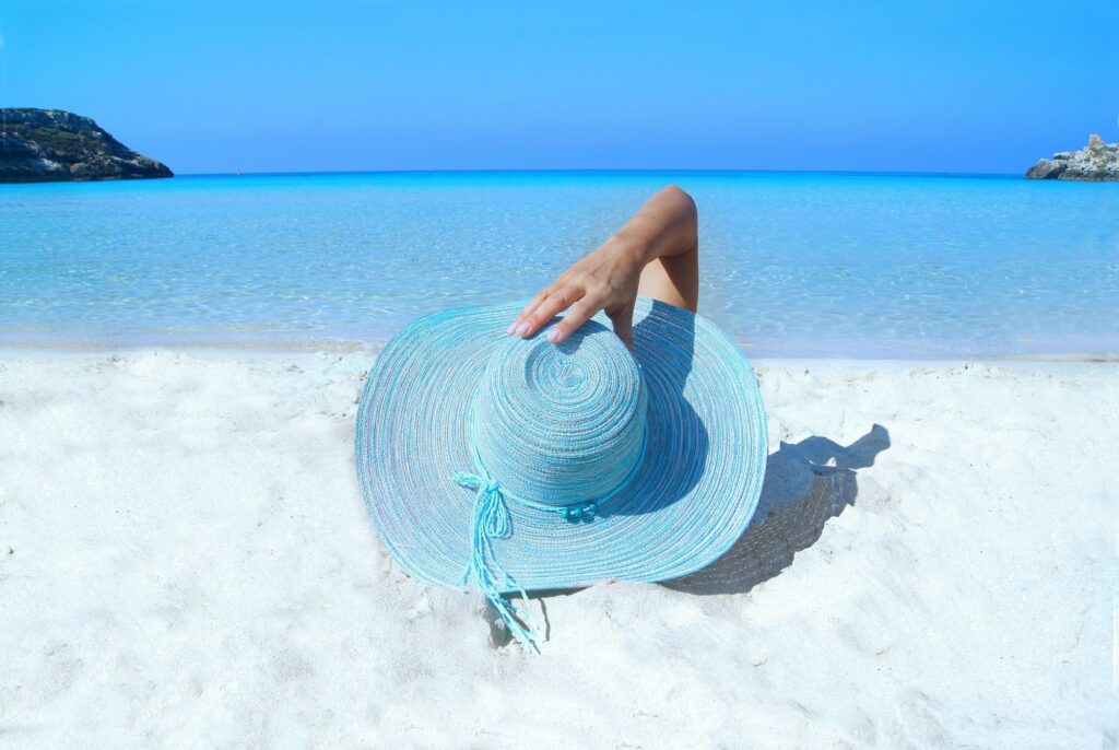 Can a tan make me more attractive?  Female on white sand with a wide brimmed sun blocking hat
