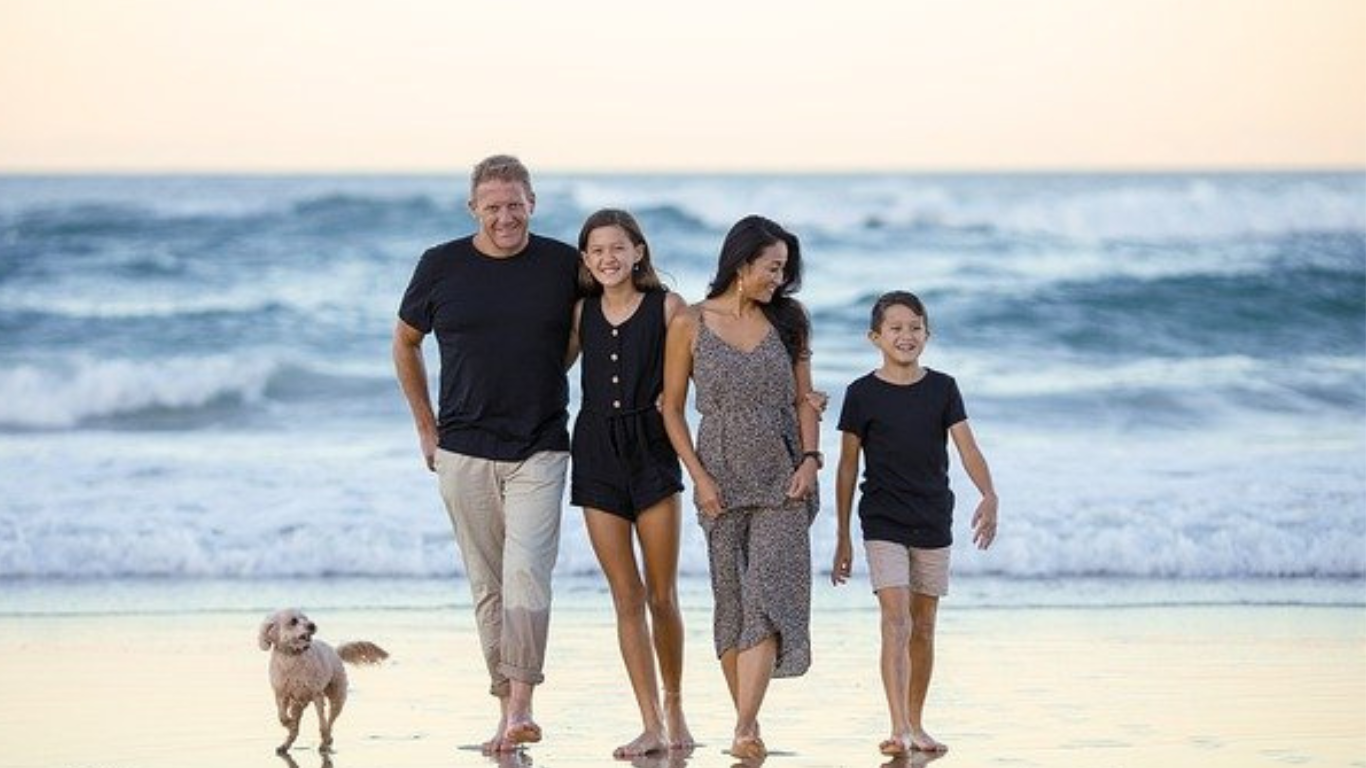A family walking on the beach dressed in normal clothing.