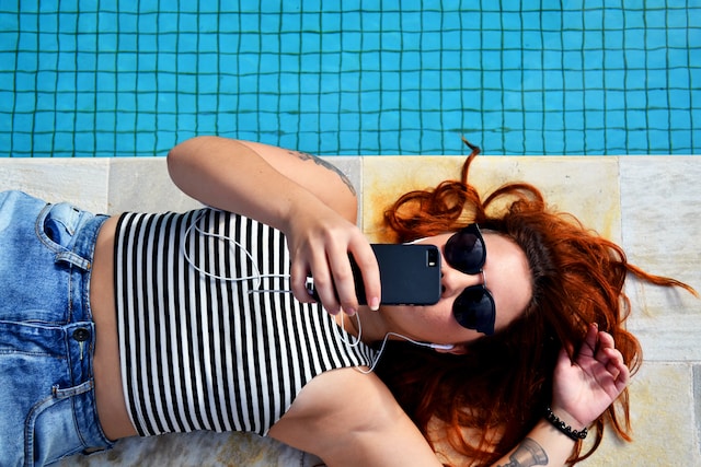 Redheaded female viewing phone for help in leaving her tanning addiction